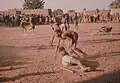 Two youngsters get ready for a wrestling match accompanied by drummers.
