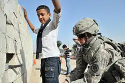 Image 5U.S. Army soldier searches an Iraqi boy, March 2011. (from History of Iraq)