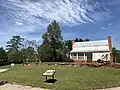 View including the yard, stone wall and a historical plaque placed by the state.