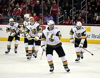 Five ice hockey players warming up before a game, facing the camera.
