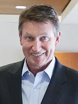 Middle-aged man with brown-grey hair wearing a dark blue jacket and a light blue dress shirt