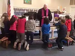 A Methodist pastor distributing ashes to confirmands kneeling at the chancel rails, 2016