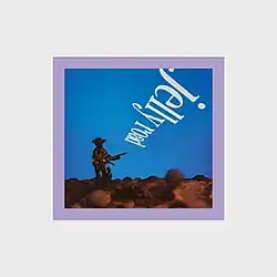 A photo of a tiny pewter figure playing guitar with thick borders around it and the album name written upside down