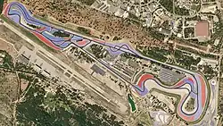 A tarmac course in a semi-rural location lined with large blue-and-red concrete run-off areas