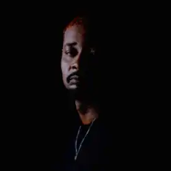 Brown facing the camera with half his face covered in shadow