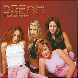 The group is sitting against a red background. The group's name appears above them in yellow dots, with the album title below it, colored in white.