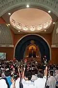 Devotees of St Thérèse hold up roses to be blessed. The flower is symbolic of the saint's intercession.