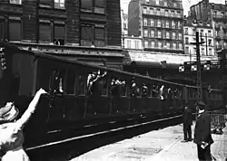 Wagons full of soldiers pull away from the station platform.