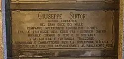 A marble gravestone on the wall of a crypt