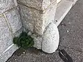 close-up photo of a stone affixed at ground level to building column