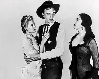 Black and white film still showing three people, with Jurado in a black dress standing next to Grace Kelly and Gary Cooper