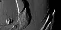 Basal scarps on Io. This image taken by NASA's Galileo spacecraft during its close flyby of Io on November 25, 1999, shows some of the curious mountains found there. The setting sun to the left exaggerates the shadows cast by the mountains. By measuring the lengths of these shadows, Galileo scientists can estimate the height of the mountains. The mountain just left of the middle of the picture is 4,000&nbsp;m (13,000&nbsp;ft) high, and the small peak to the lower left is 1,600&nbsp;m (5,200&nbsp;ft) high.