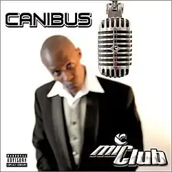 A blurred image of a bald man wearing a black suit and white dress shirt, looking up at a microphone. The artist's name appears on the top left corner in black and the album title is on the bottom right corner in white.