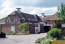 A photograph showing an L-shaped oast building with two square cowls protruding from a V-shaped roof