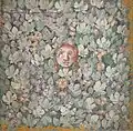 Mask amid bunches of grapes and vines