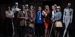 An assortment of characters and mannequins in a darkened room