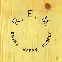 A wood grain with the artist name and song title carved into it