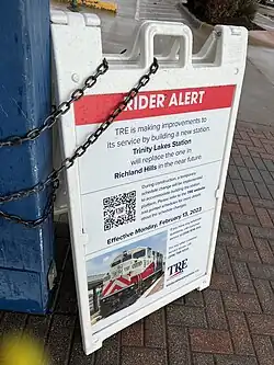 Signage at CentrePort/DFW Airport station announcing the future closure and replacement of Richland Hills station. The text says, "RIDER ALERT: TRE is making improvements to its service by building a new station. Trinity Lakes Station will replace the one in Richland Hills in the near future. During construction, a temporary schedule change will be implemented to accommodate building the station platform. Please refer to the TRE website and printed schedules for more details about the schedule changes. Effective Monday, February 13, 2023