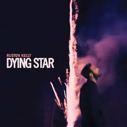 A firework explodes to the sky behind a man looking up. The artist's name and album title appear beside the firework, colored orange and white respectively.