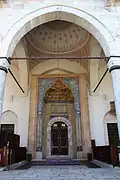 The main entrance portal with an islamic arch before entering, and intricately carved muqarnas on the portal and on the dome pendentives above. There is also an ablaq design around the main entrance as well.