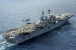 A CH-53E Super Stallion lifting pallets off USS Bataan