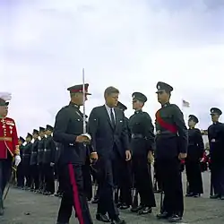 US President John F. Kennedy, escorted by a Bermuda Militia Artillery officer in Royal Artillery blue No. 1 dress, inspects green-uniformed riflemen of the Bermuda Rifles in 1961