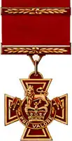 A bronze cross pattée bearing the crown of Saint Edward surmounted by a lion with the inscription Pro Valore. A Bar crosses the crimson ribbon attached to the medal.