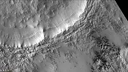 Short dark streaks are dark fans caused by outgassing of carbon dioxide and dark material. Layers are easily visible in the wall of the crater. Note: this is an enlargement of the previous image of McMurdo. Picture taken with CTX camera (on Mars Reconnaissance Orbiter).